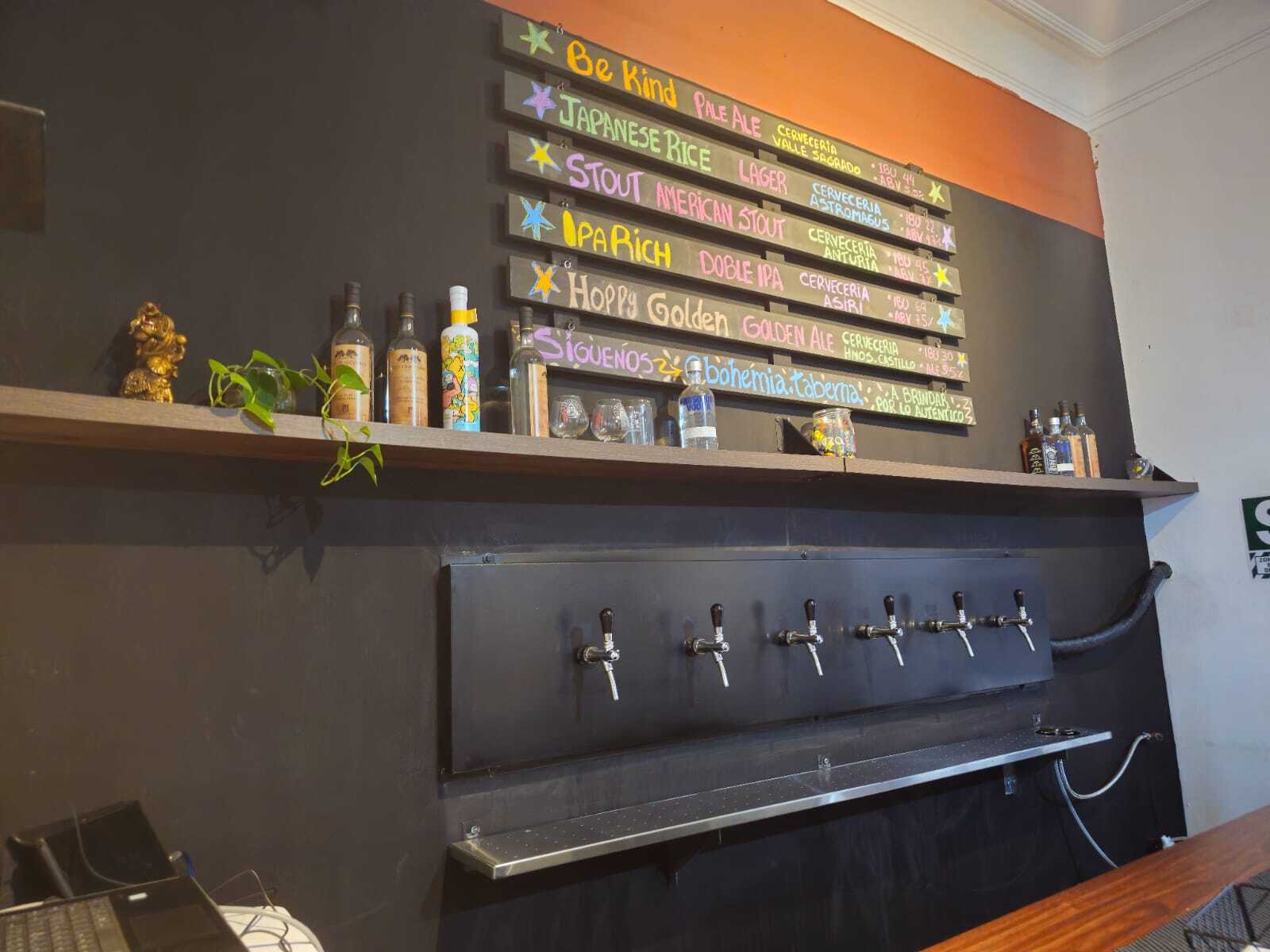 Imagen de nuestra barra con variedad de estilos de cervezas artesanales, resaltando todo lo que ofrece el bar: música en vinilo, snacks únicos, eventos, karaoke y una vida nocturna auténtica para disfrutar con amigos